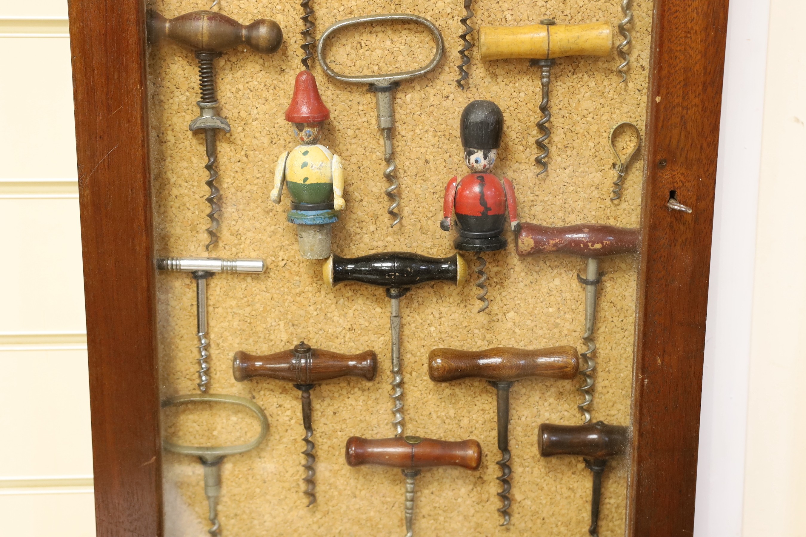 A collection of vintage corkscrews, some novelty, in glazed mahogany vase with key